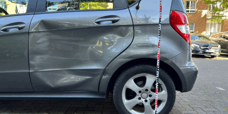 Heckschaden an grauer Mercedes A-Klasse: stark verbeulte, geknickte hintere Tür – dokumentiert zur Gutachtenerstellung in Köln.